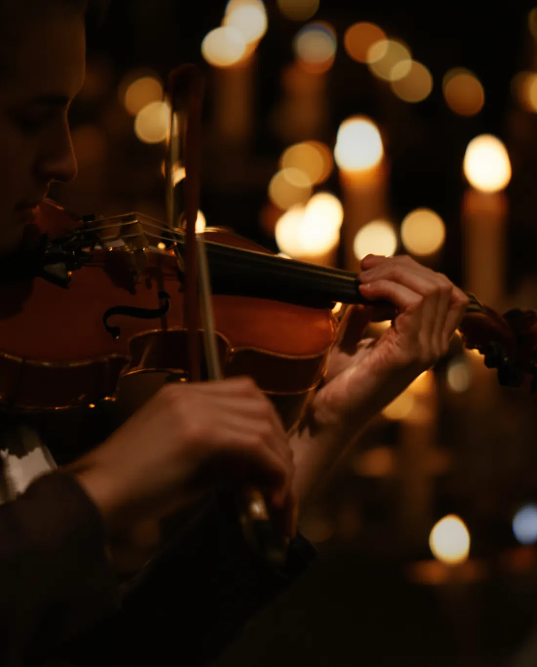 Geigerin bei einem Candlelight-Konzert, im Hintergrund unscharfe Kerzenflammen